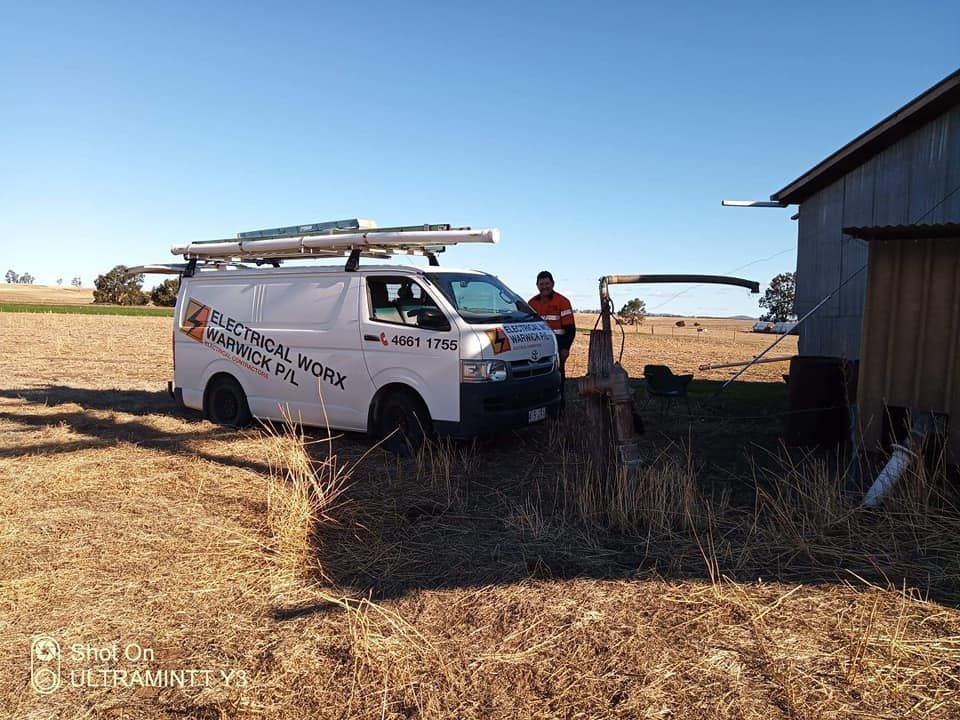 A white van is parked in a field next to a shed. — Electrical Worx Warwick P/L In Warwick, QLD