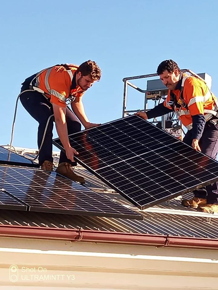 A Person Is Installing Solar Panels On A Roof — Electrical Worx Warwick P/L In Warwick, QLD