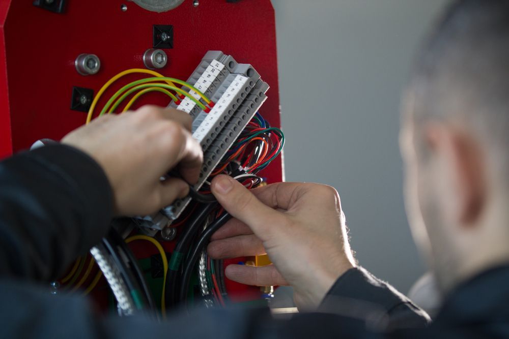A Man Is Working On A Machine With Wires And Connectors — Electrical Worx Warwick P/L In Warwick, QLD
