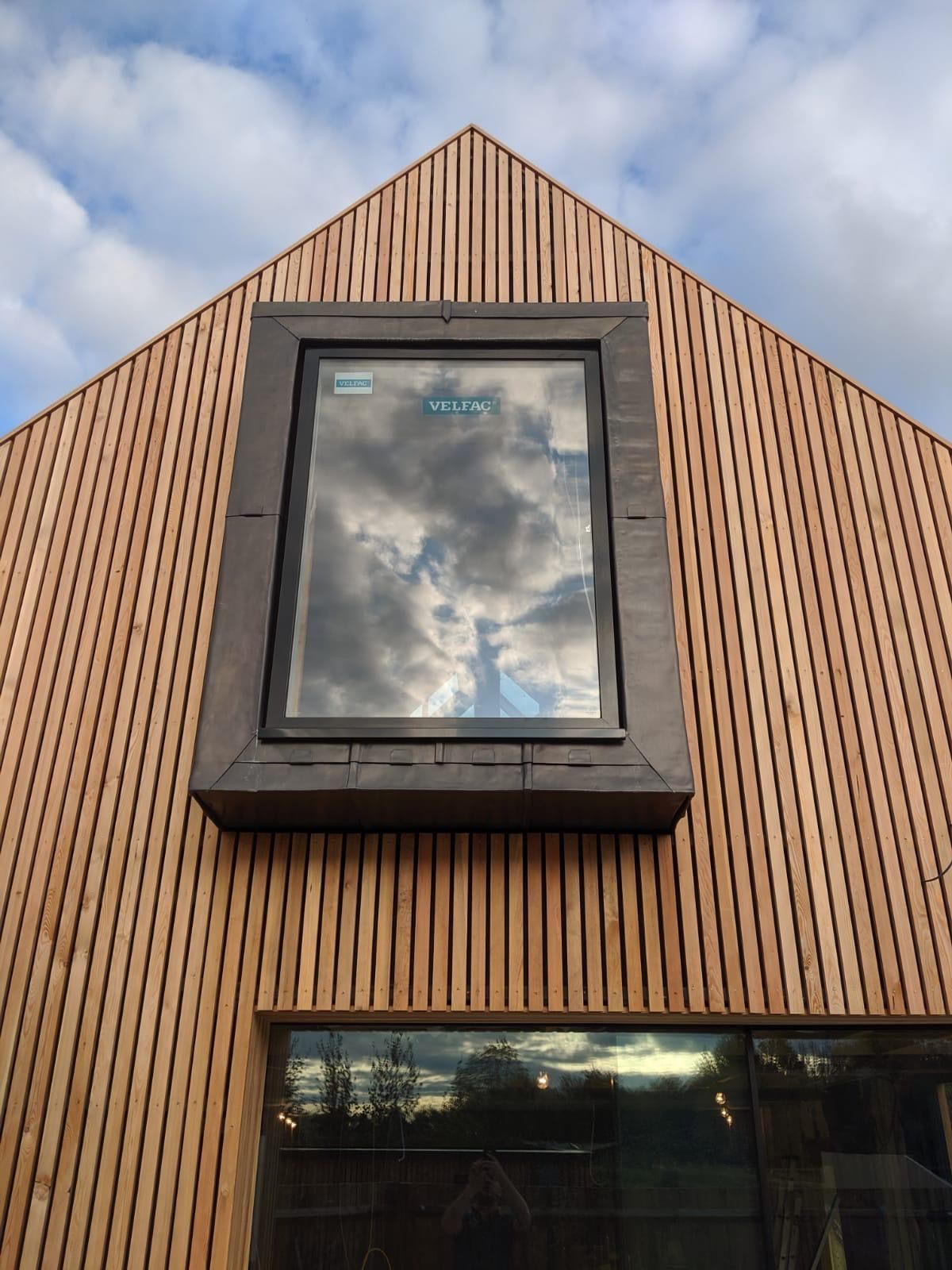 Window covered with lead waterproofing and wooden industrial wall cladding