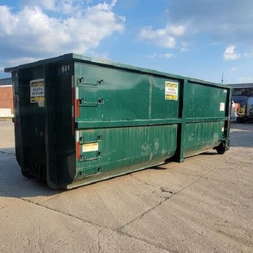 Bright green dumpster on wheels, outdoors near building materials.