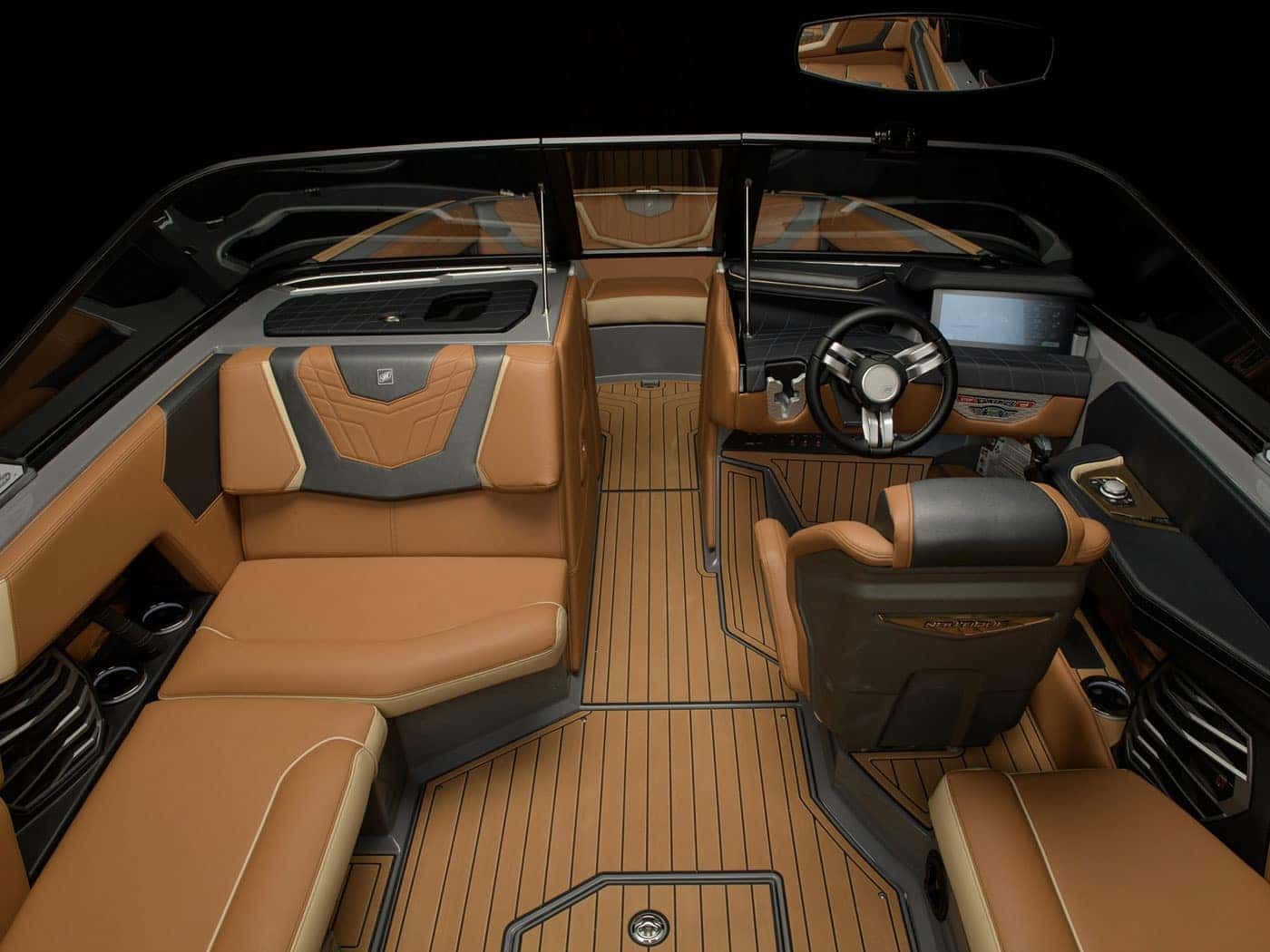 Boat interior with brown and black seating, wooden floor, and steering wheel.