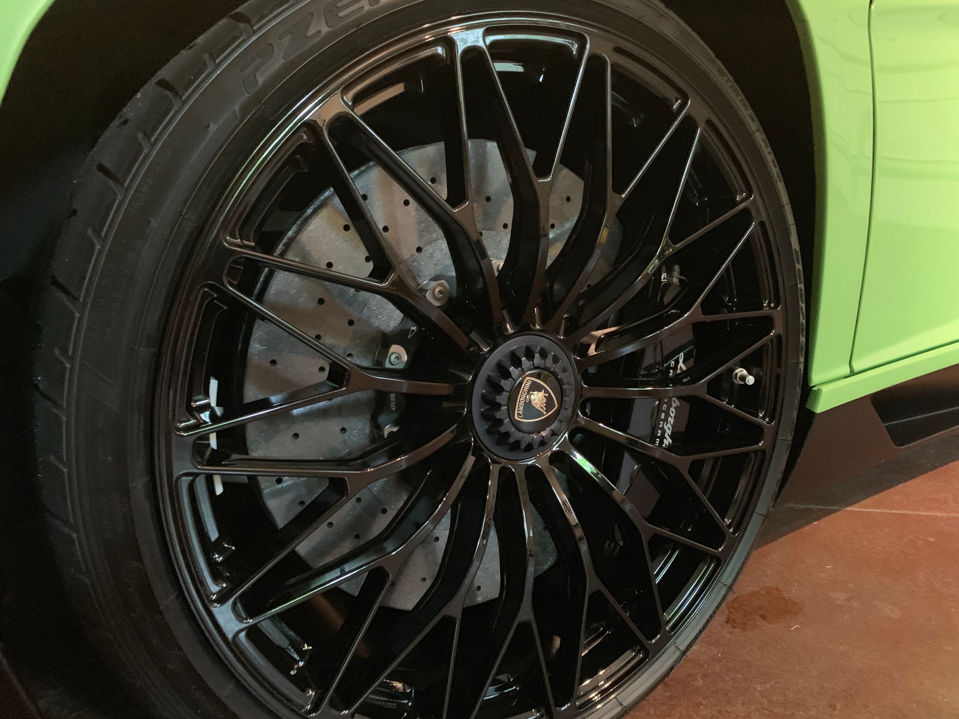 Black Lamborghini wheel on a green car.