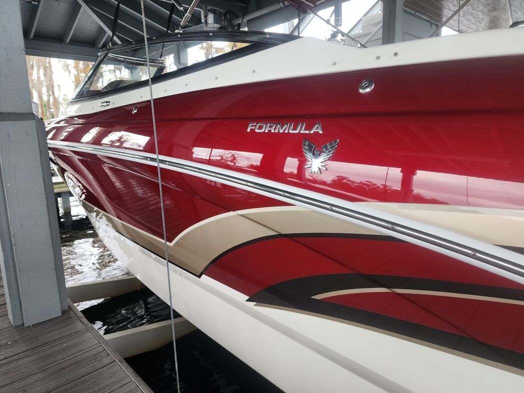 Red and white Formula boat with gold accents at a dock.