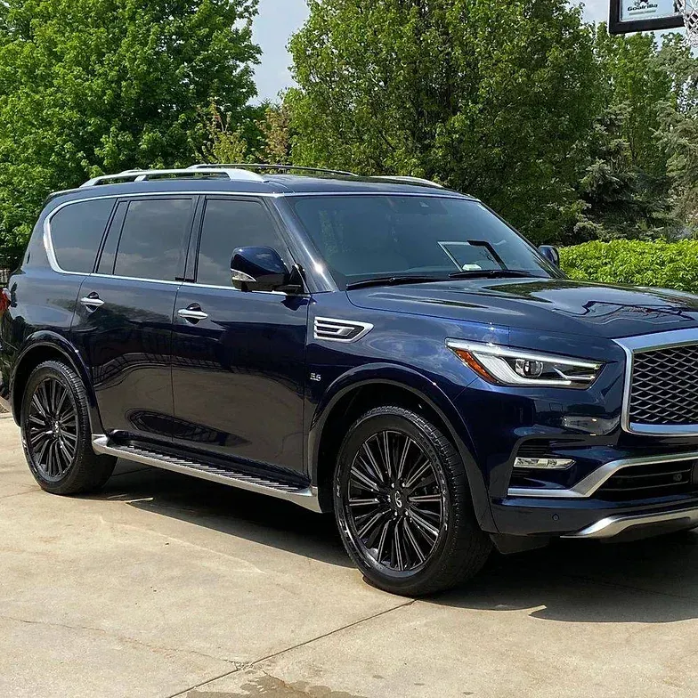 Dark blue Infiniti QX80 SUV with black rims, parked outside on a sunny day.