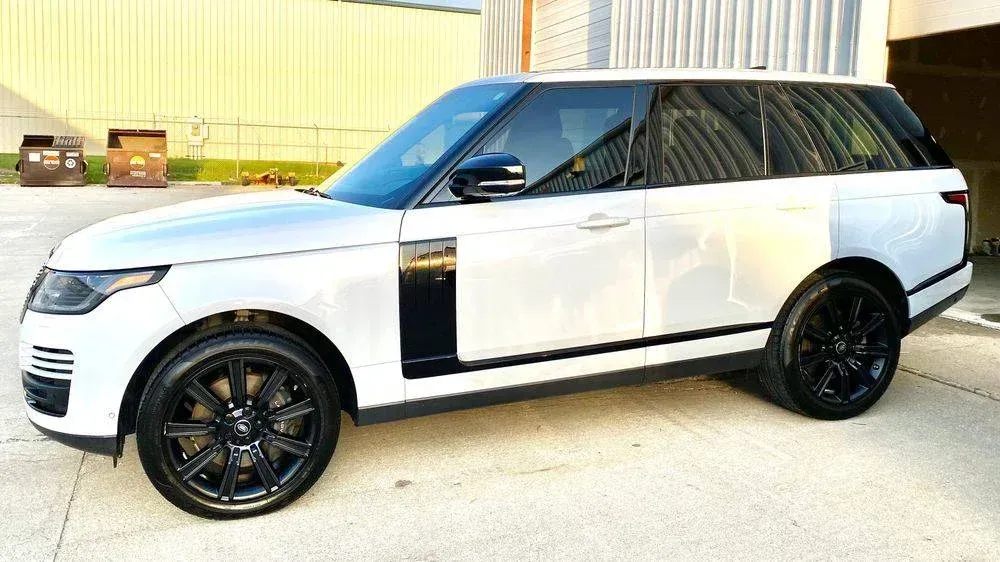 White Range Rover SUV with black accents and rims parked outside.