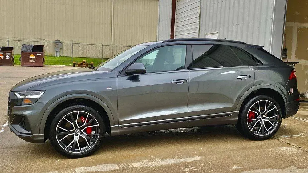 Gray Audi Q8 SUV with black rims and red brake calipers parked in front of a building.