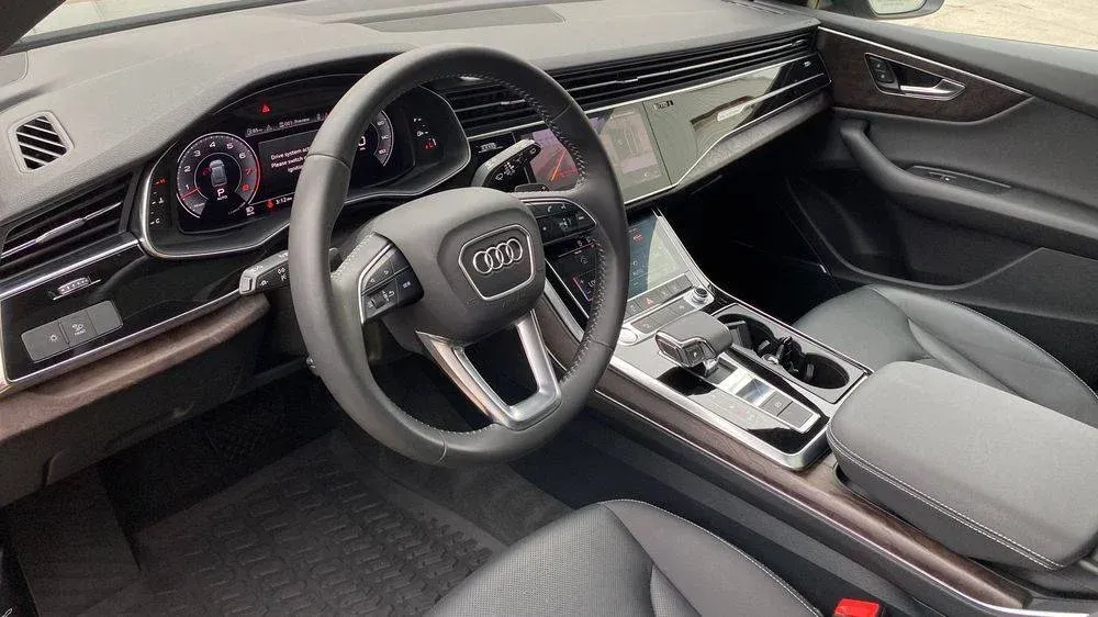 Black leather interior of an Audi, featuring the steering wheel, dashboard, and center console.