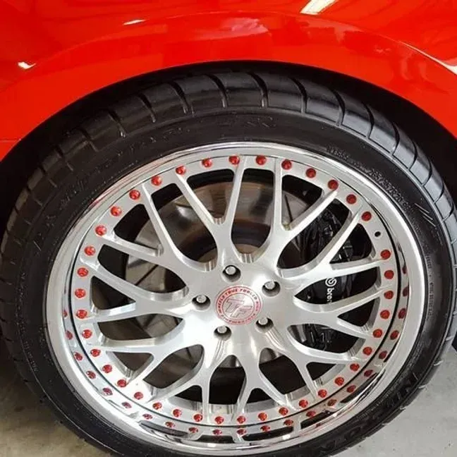 Close-up of a red car wheel with a silver rim, red accents, and a black tire.