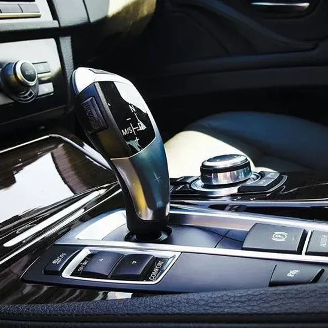 Car interior with a gear shift lever and control buttons.