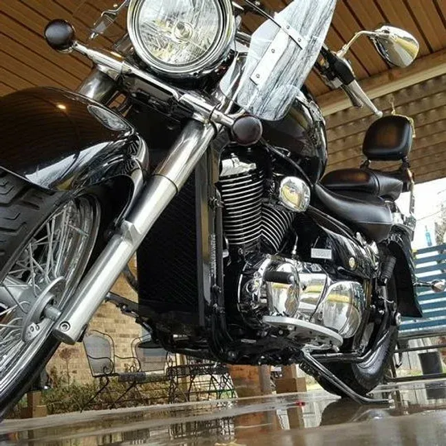 Black motorcycle with chrome accents parked under a covered area.