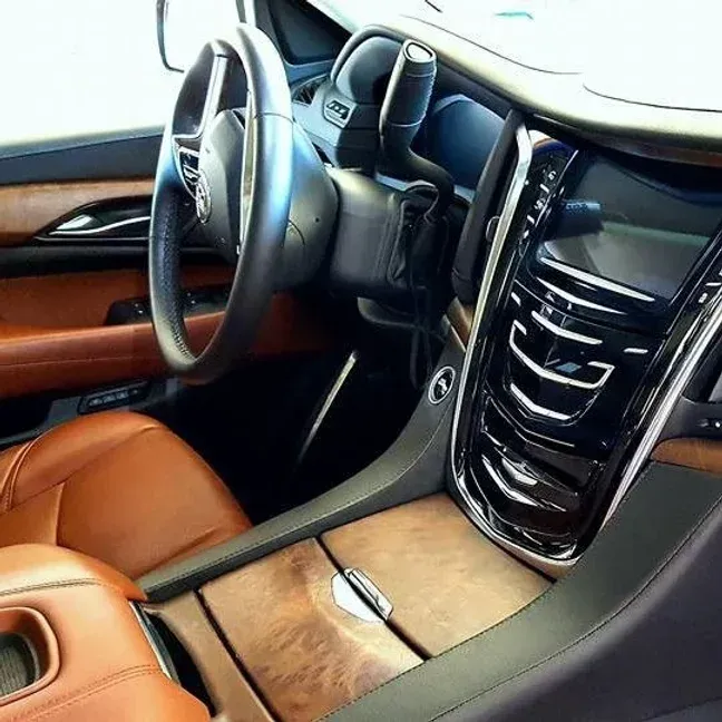 Brown leather Cadillac interior with wood trim, chrome accents, and steering wheel.