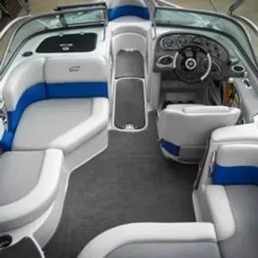 Interior of a white and blue boat with seats, steering wheel, and control panel.