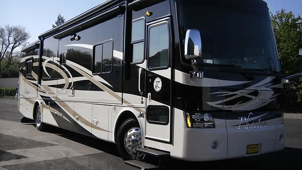Large, black and cream RV parked outdoors.
