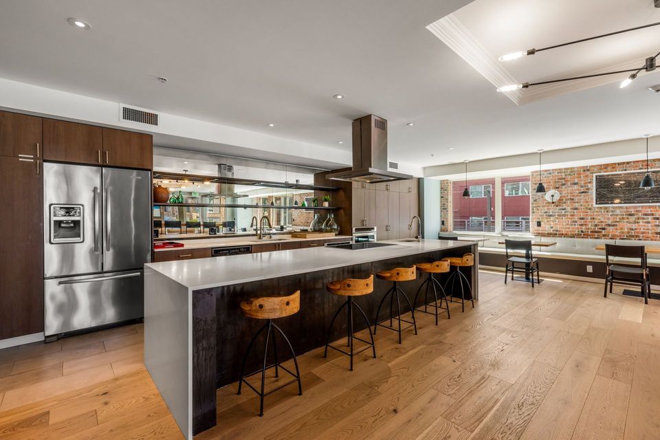 A large kitchen with stainless steel appliances , granite counter tops , and wooden floors.