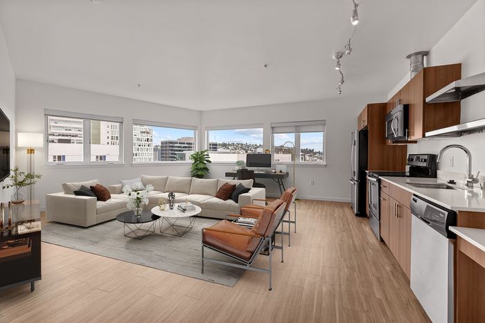 A living room with a couch , coffee table , chairs and a kitchen.