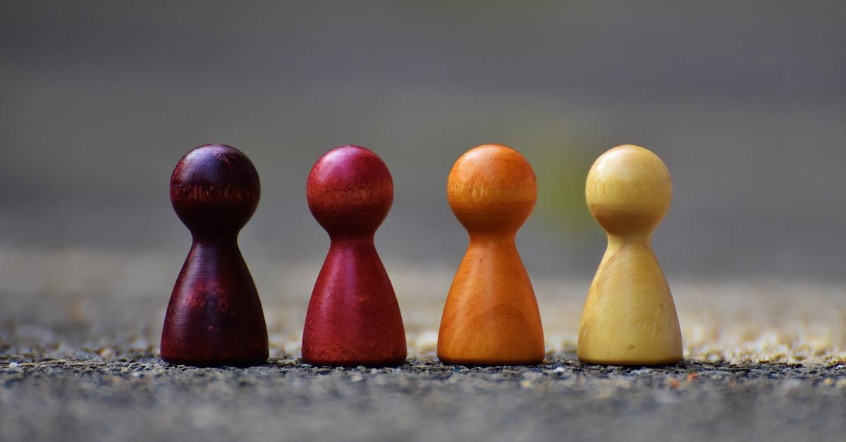 Four wooden peg dolls are lined up in a row on the ground.