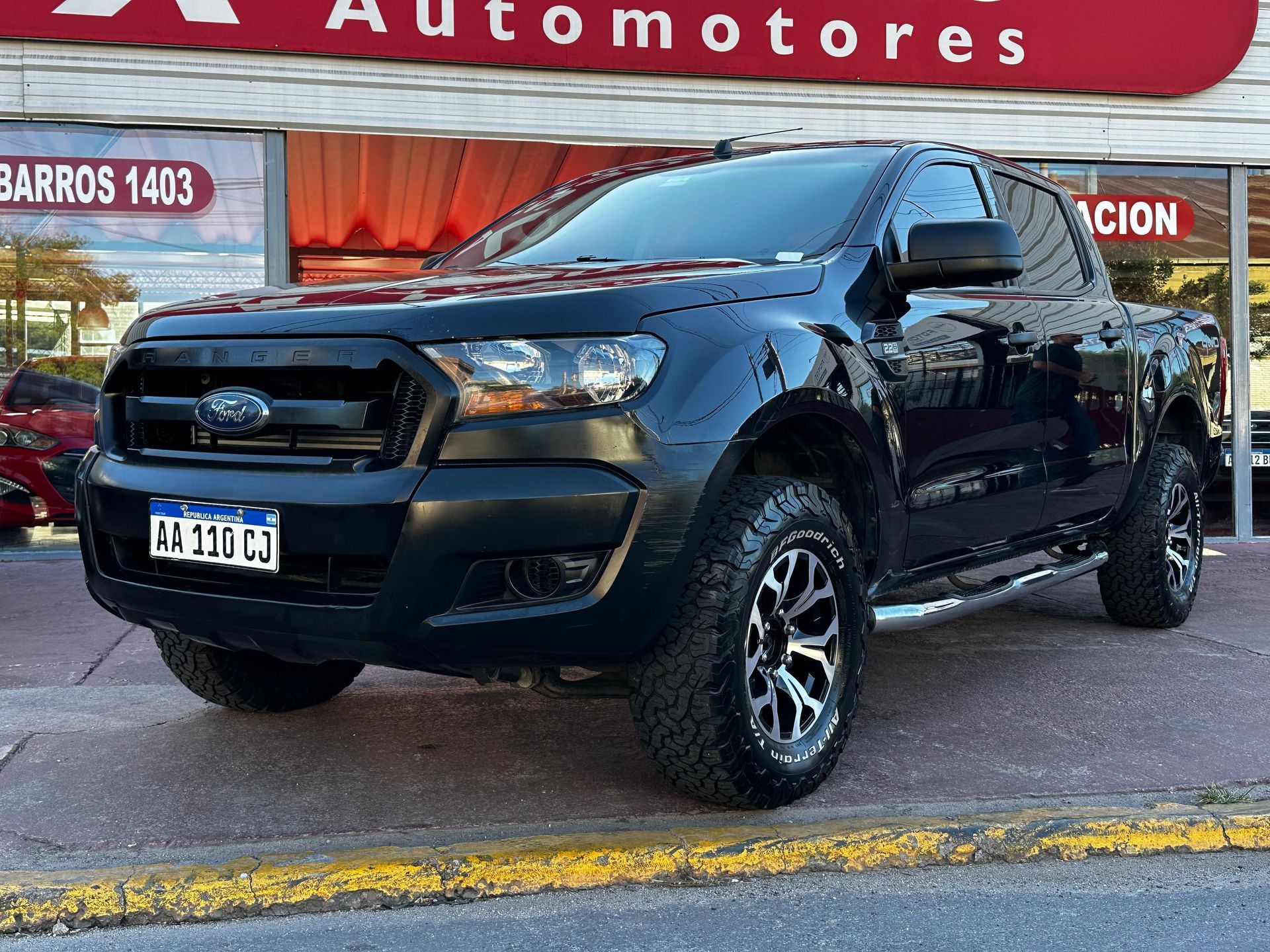 Un camión negro está estacionado frente a un concesionario de automóviles.