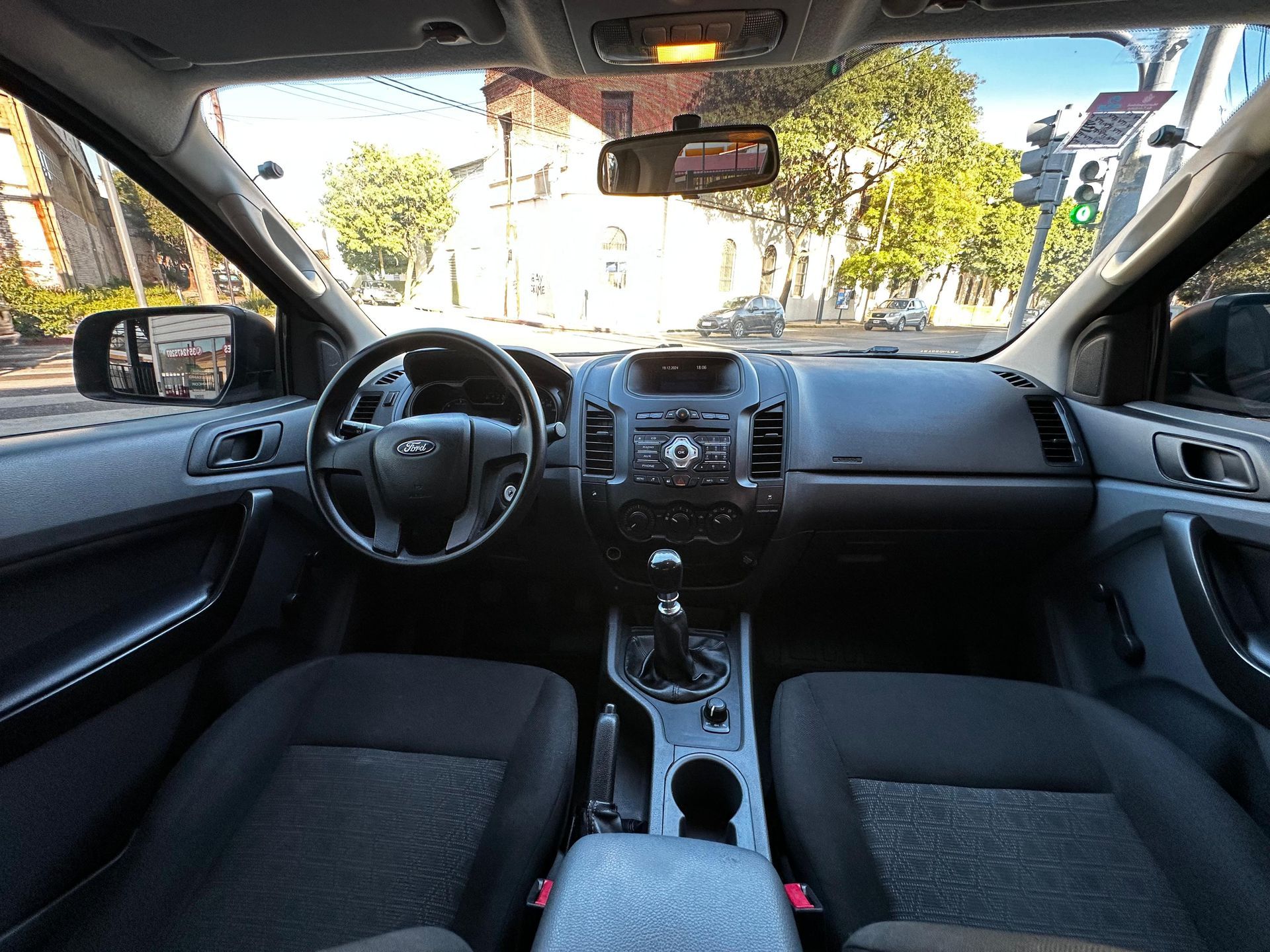 El interior de un coche con un volante y un espejo retrovisor.