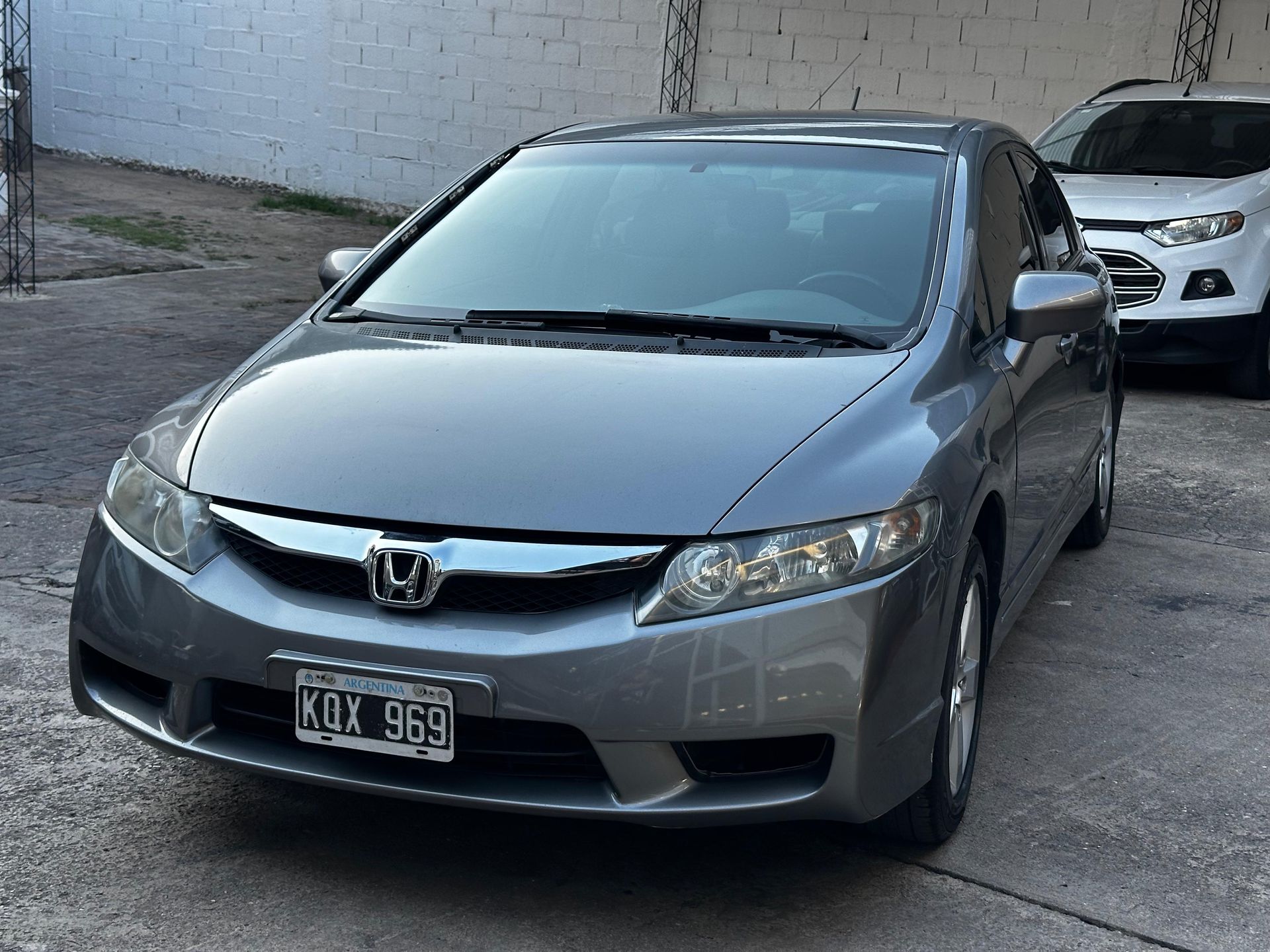 Un Honda Civic gris está estacionado en un estacionamiento.