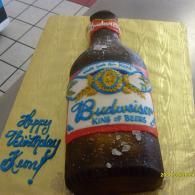 Budweiser beer bottle on a yellow cloth with blue “Happy Birthday” writing