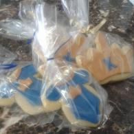 Assorted cookies in a clear plastic bag, iced in blue and tan.