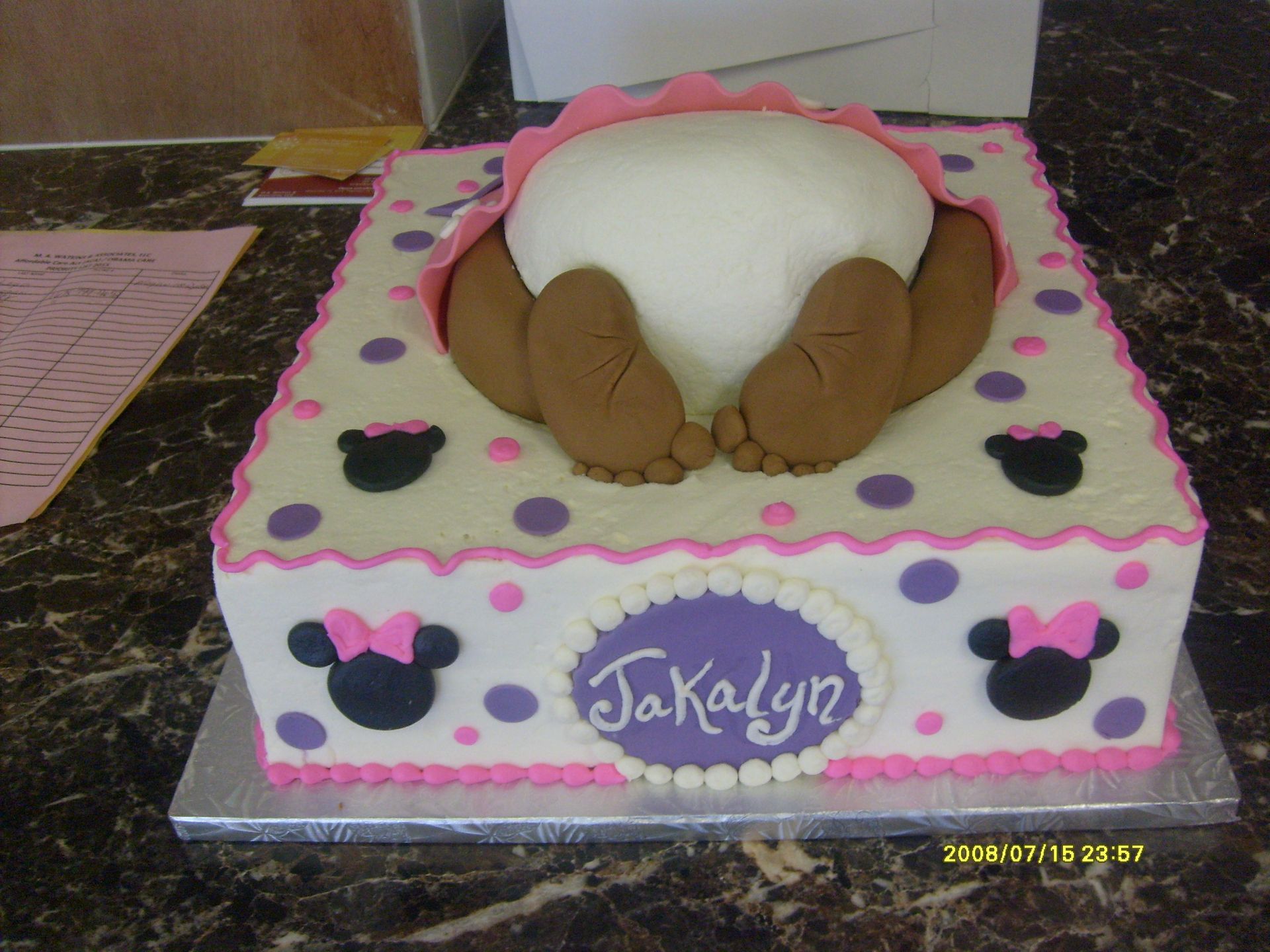 Decorated pink-and-white baby shower cake with a sleeping baby topper and “KaKalyn” plaque