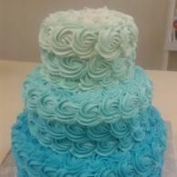 Three-tier ombré cake with blue to white rosette frosting