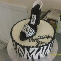 Black-and-white zebra-print cake with a high-heeled shoe topper and “Happy Birthday Kim” written on top
