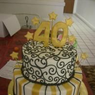 Decorated birthday cake with gold “40” topper and stars on a striped tablecloth