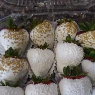 Assorted chocolate-covered strawberries, some topped with white and gold sprinkles, in a tray