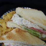 Sandwich with lettuce and tomato on a plate, with chips on the side