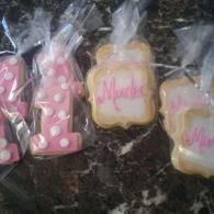 Wrapped pink and white decorated cookies in plastic bags on a dark countertop