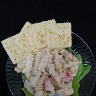 Crackers on a plate with a creamy salad-like dish and a green leaf garnish
