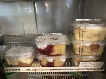 Plastic containers of layered desserts on a refrigerated shelf in a display case.