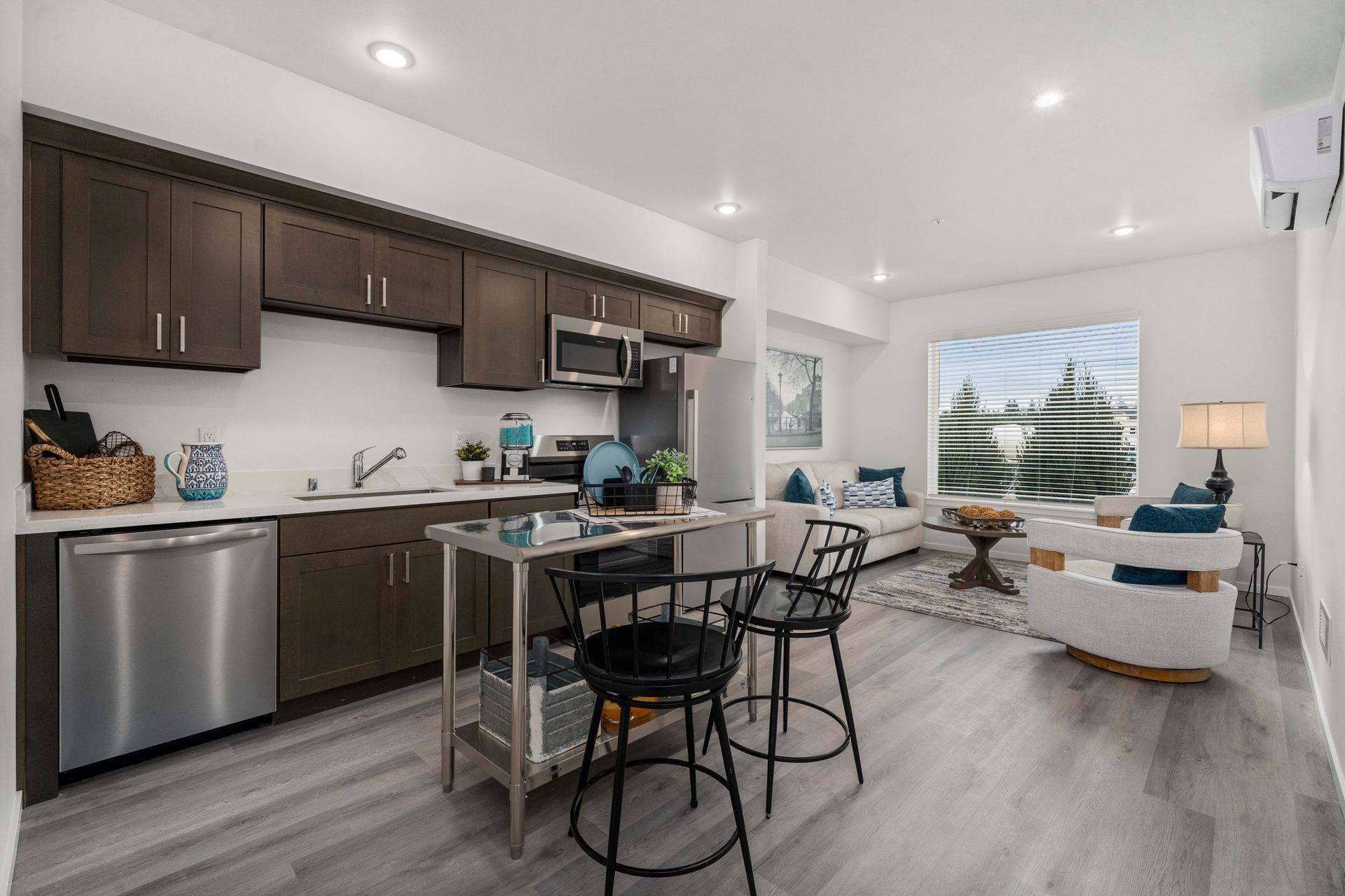 A kitchen with stainless steel appliances , wooden cabinets , a table and chairs.