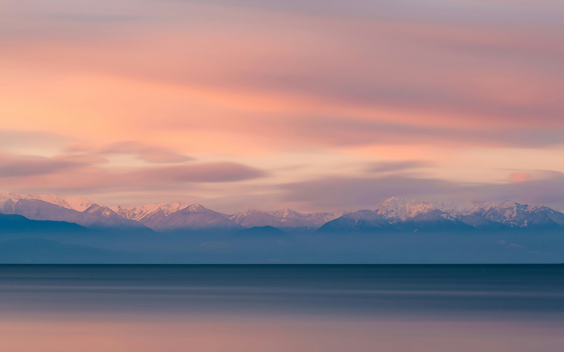 A sunset over a lake with mountains in the background