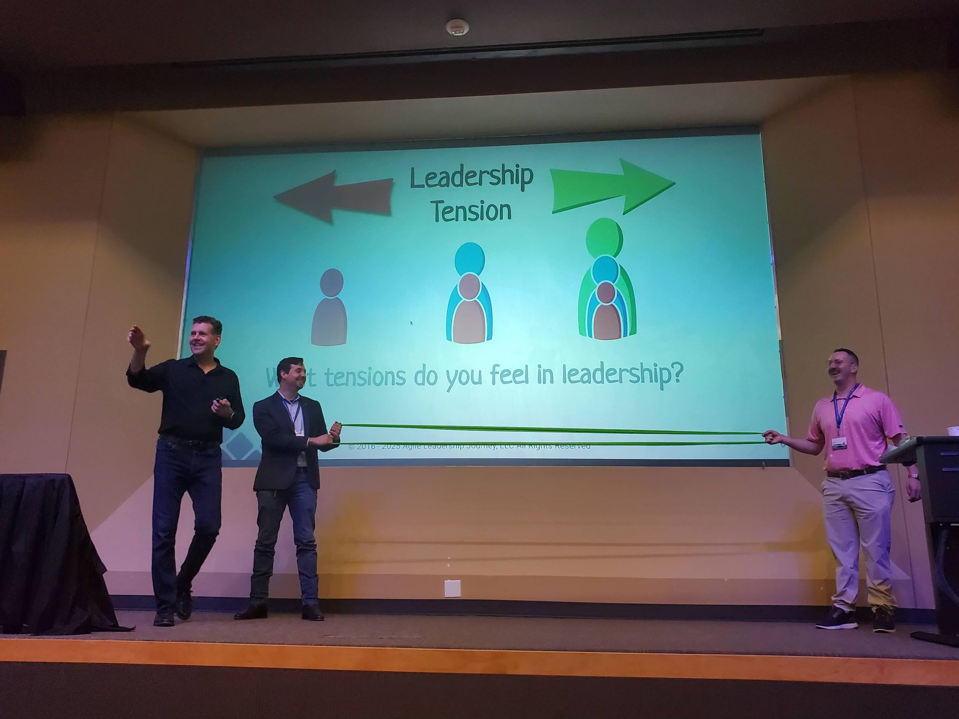 Three men on stage presenting, with 