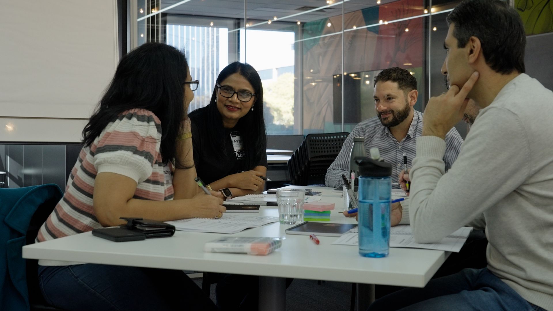 A group of people are talking around a table in a workshop.