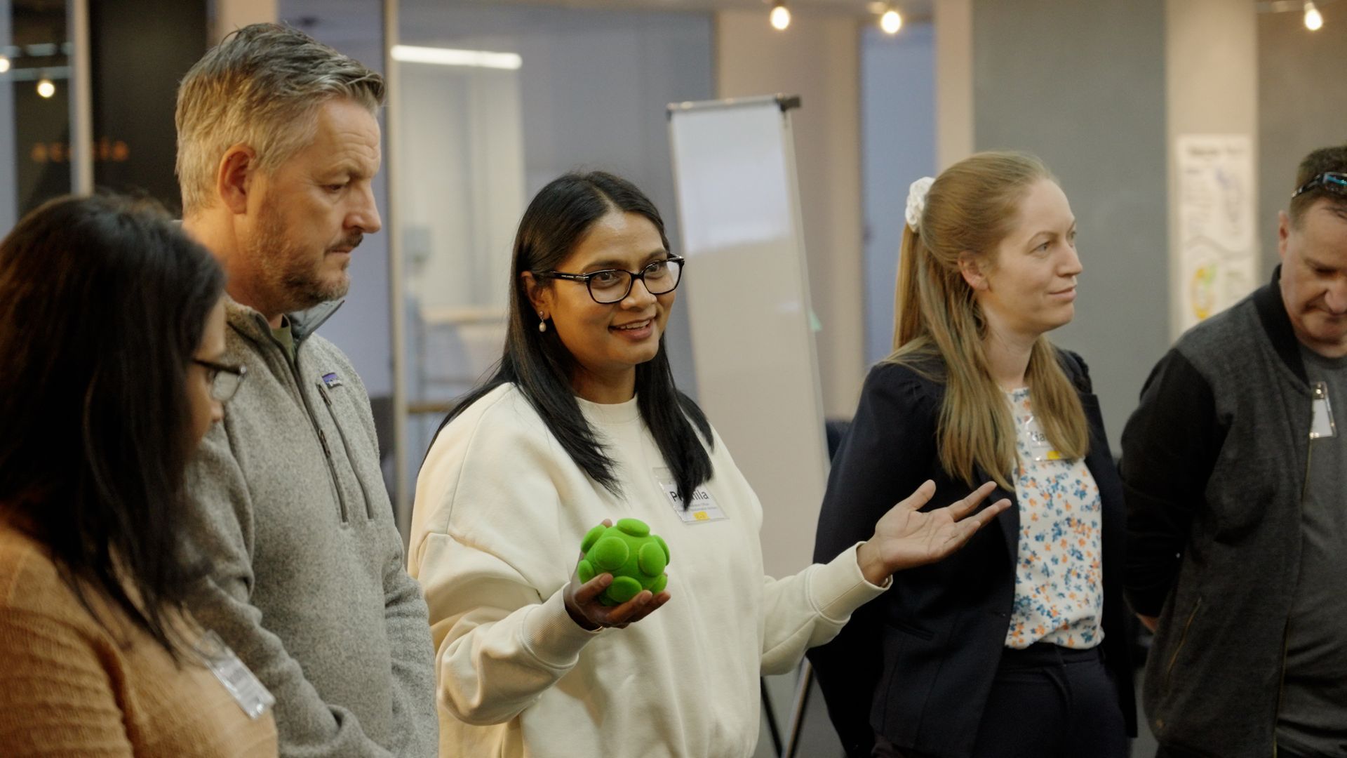 A group of people are standing around a woman holding a green ball.
