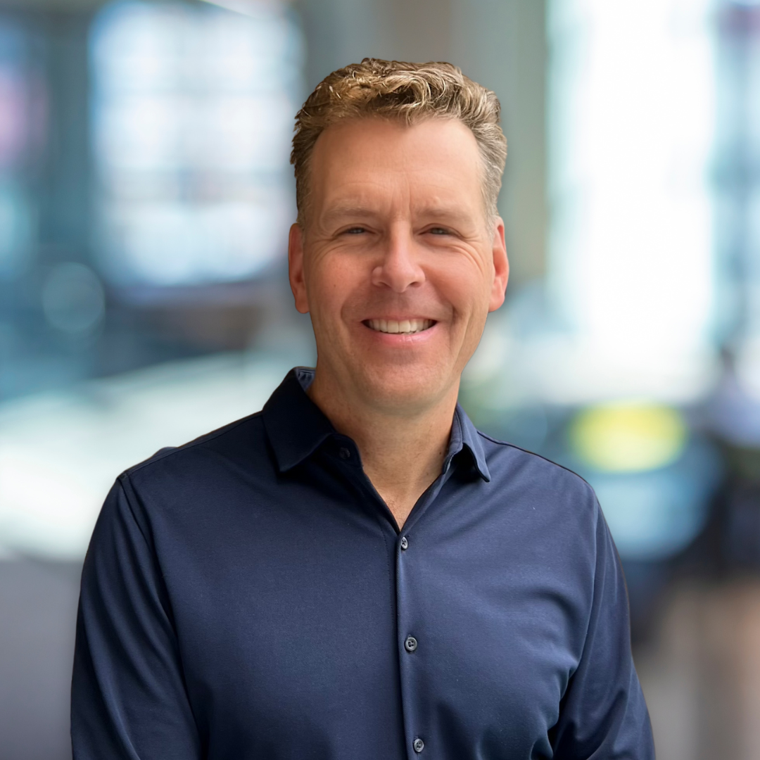 A man in a blue shirt is smiling for the camera.