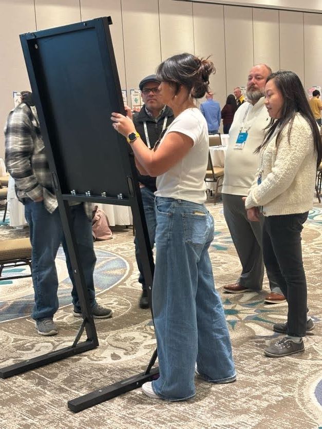 Leaders collaborating at a leadership development workshop, working together around a shared board to address real organizational challenges.