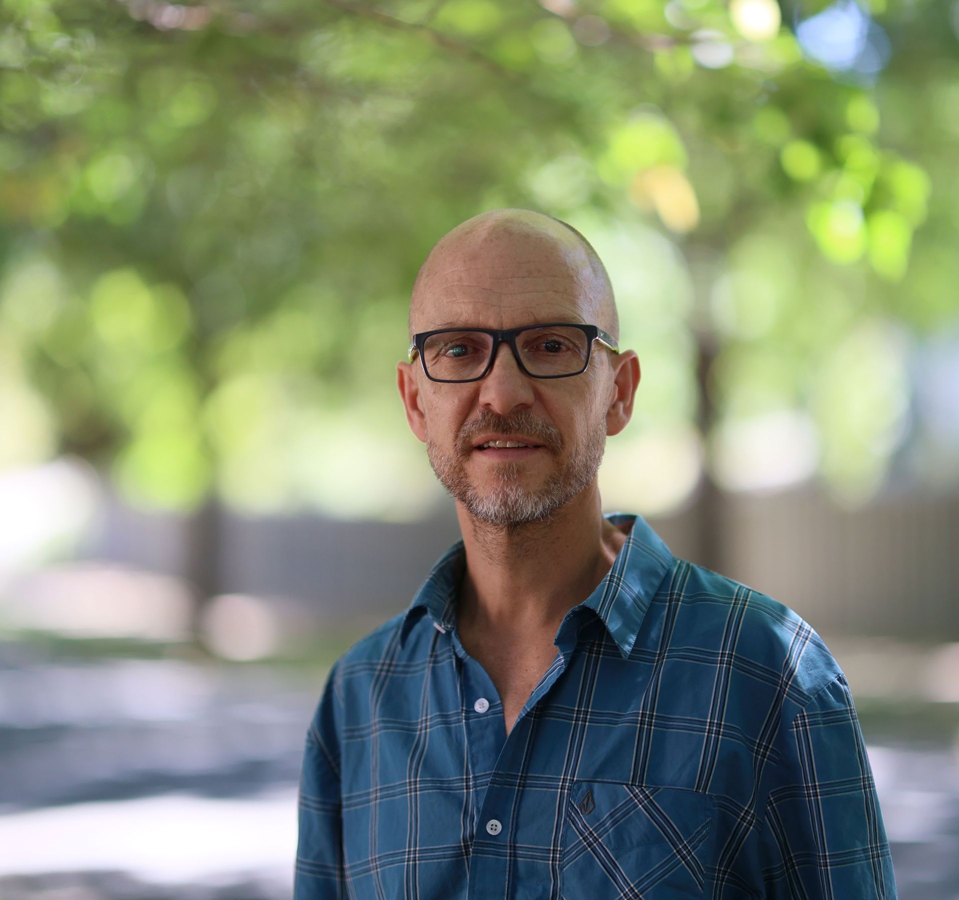 Headshot of Mark Flanagan in a blue shirt with trees in the background