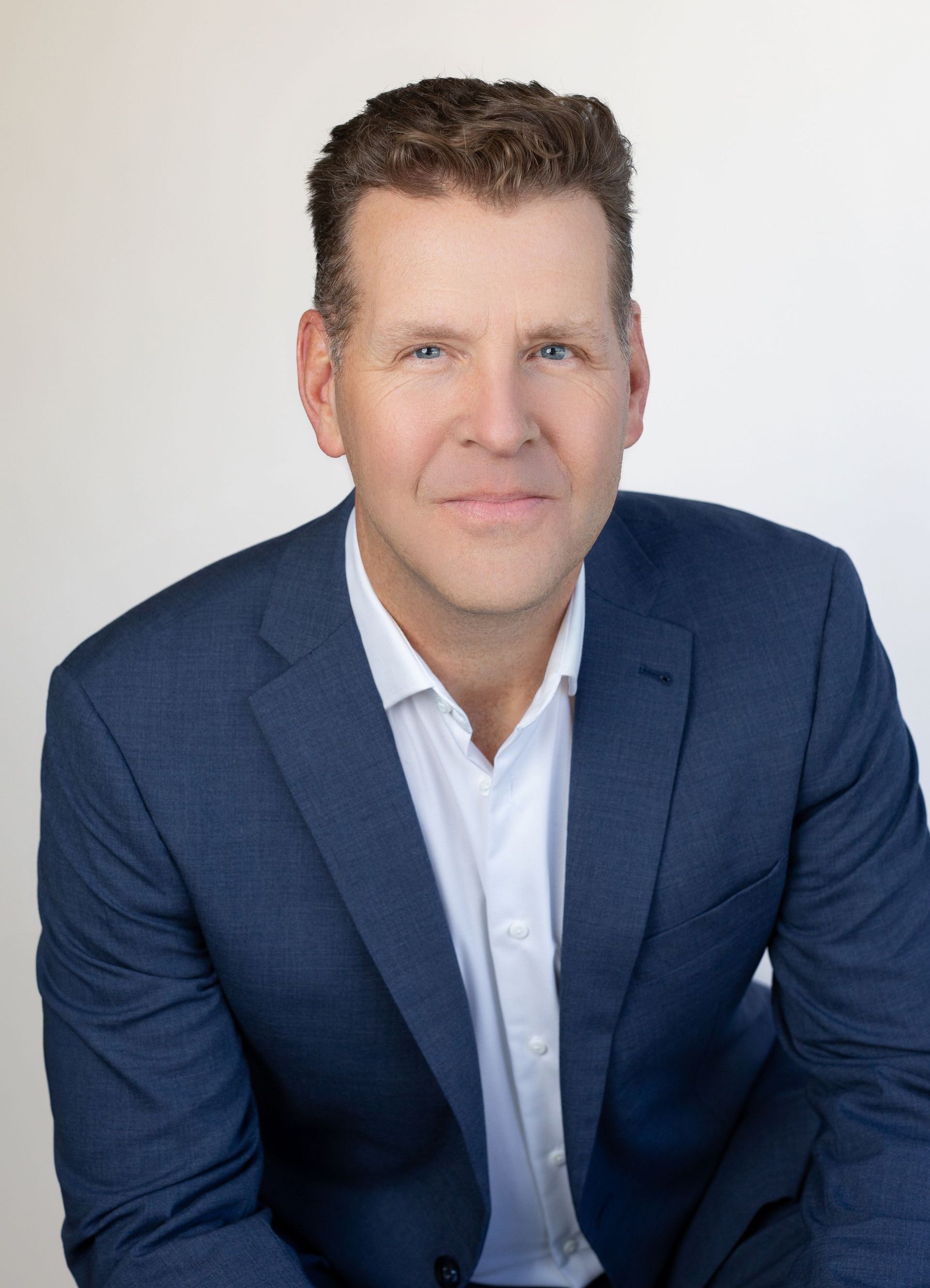 A man in a blue suit and white shirt is sitting down.