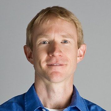 Color headshot of Brad Swanson, a white man with short blonde hair and green eyes. He is wearing a blue collared button up shirt
