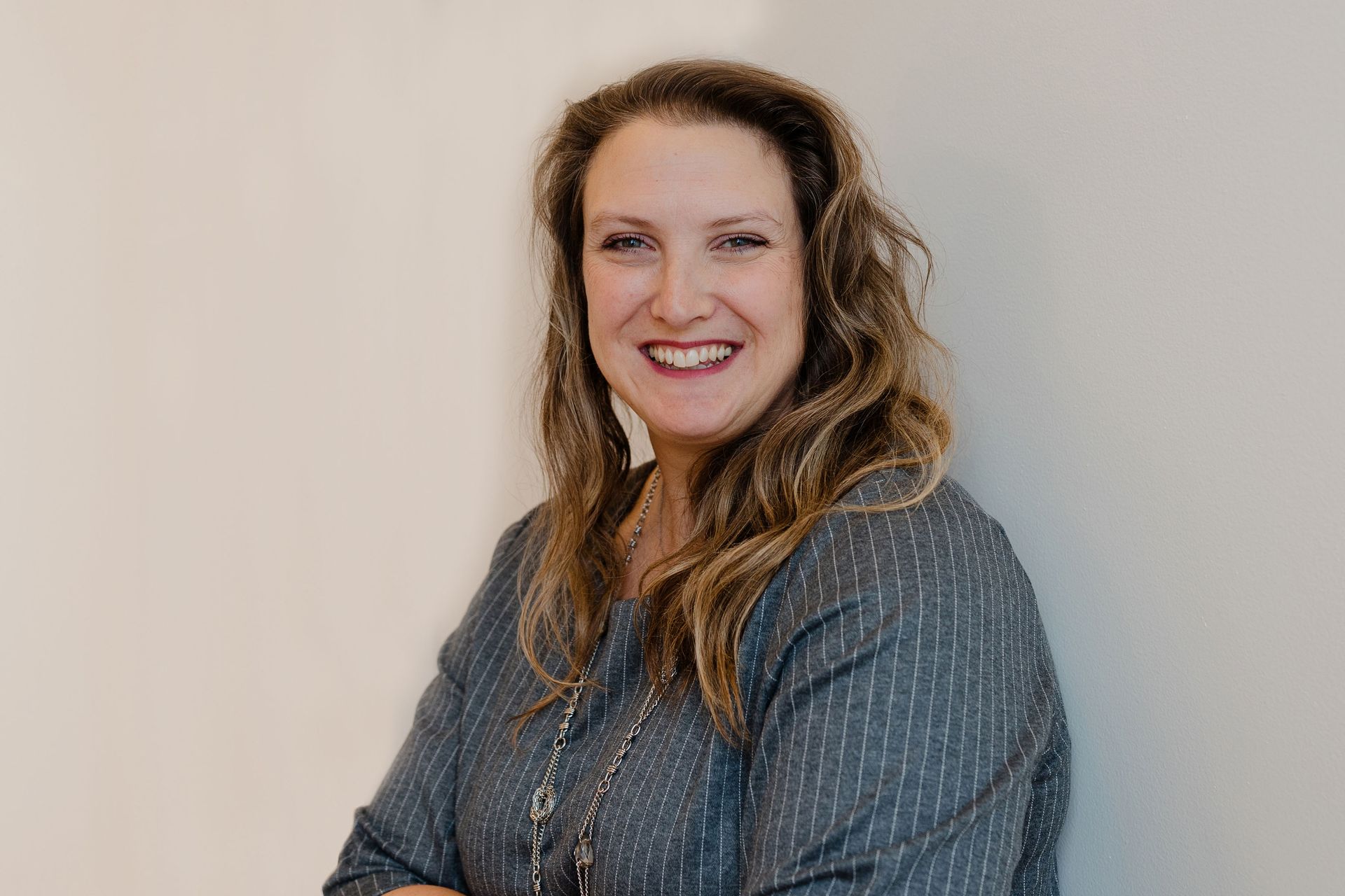 Christina Carlson is standing in front of a white wall and smiling.