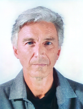 A man with gray hair is wearing a gray jacket and a black shirt.