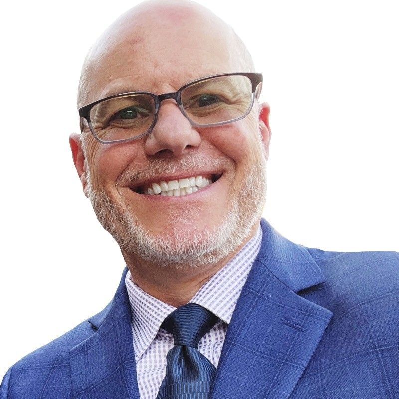 A man wearing glasses and a blue suit is smiling