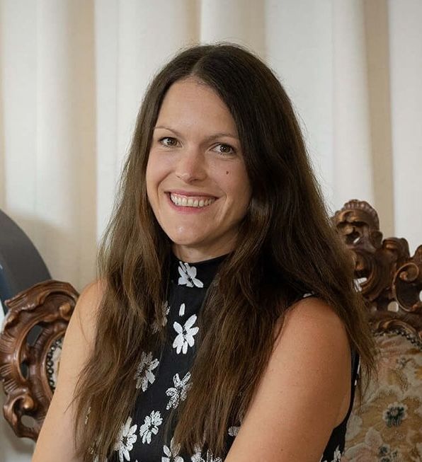 A woman with long hair is smiling while sitting on a couch