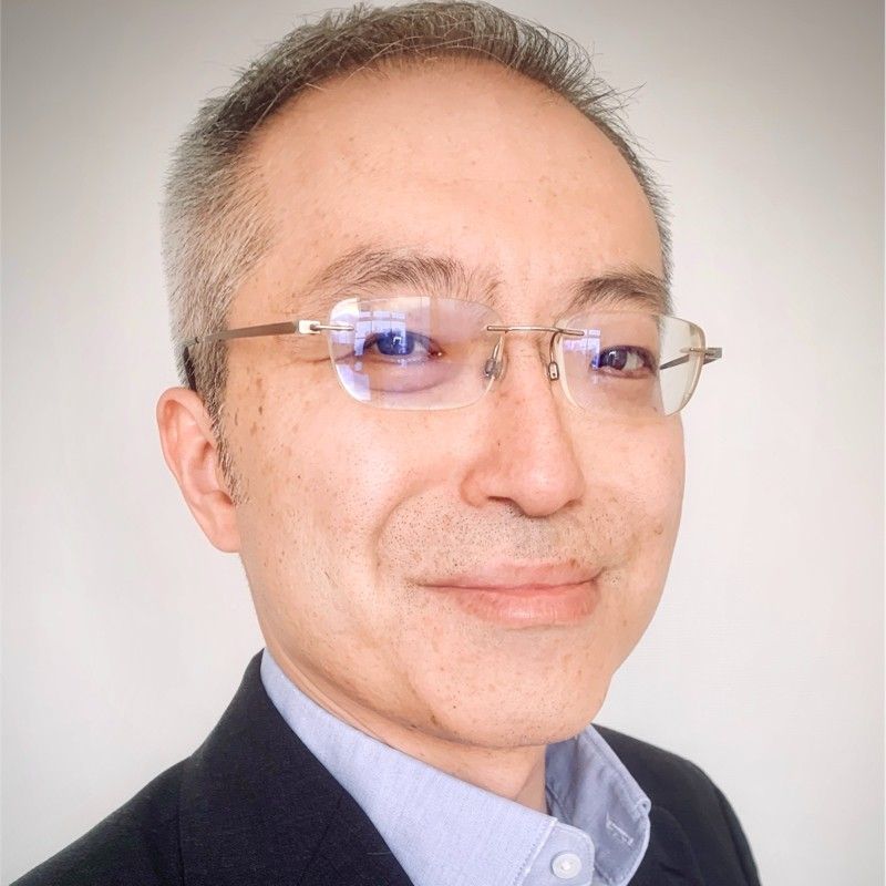 A man wearing glasses and a suit is smiling for the camera.